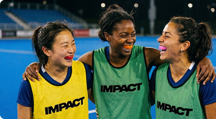 Team of players wearing IMPACT bibs smiling together